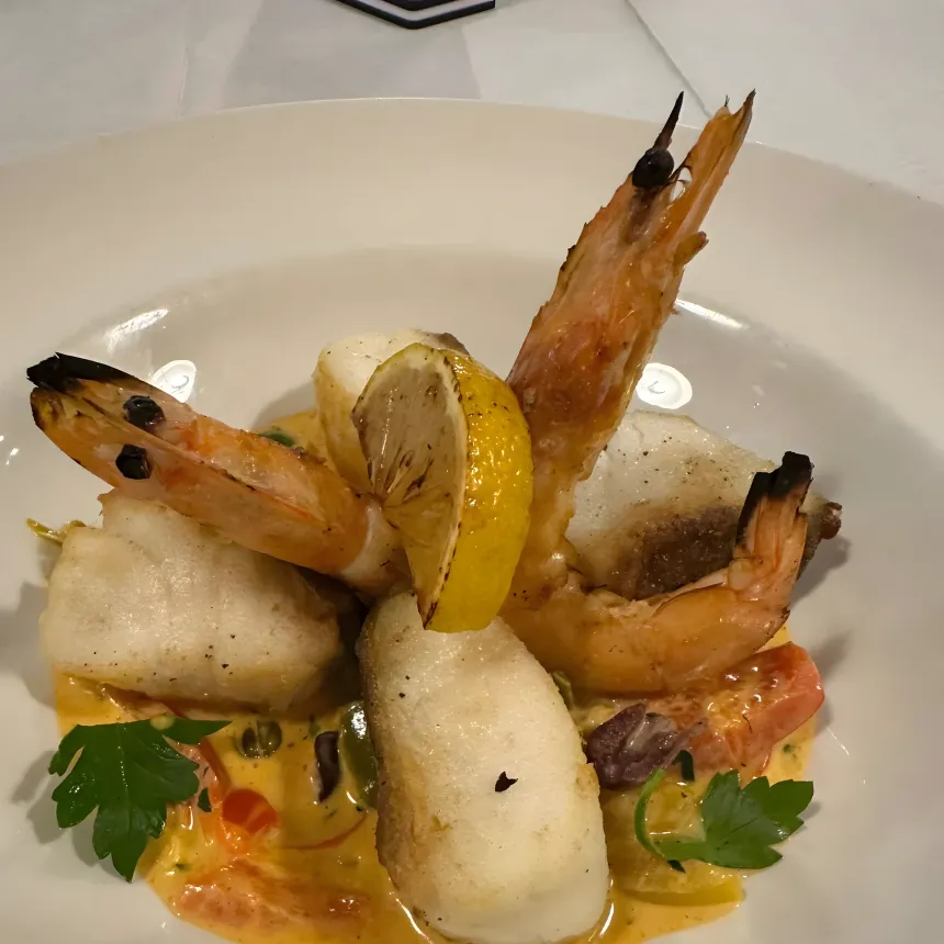 Grilled fish and prawns in a creamy sauce with vegetables.