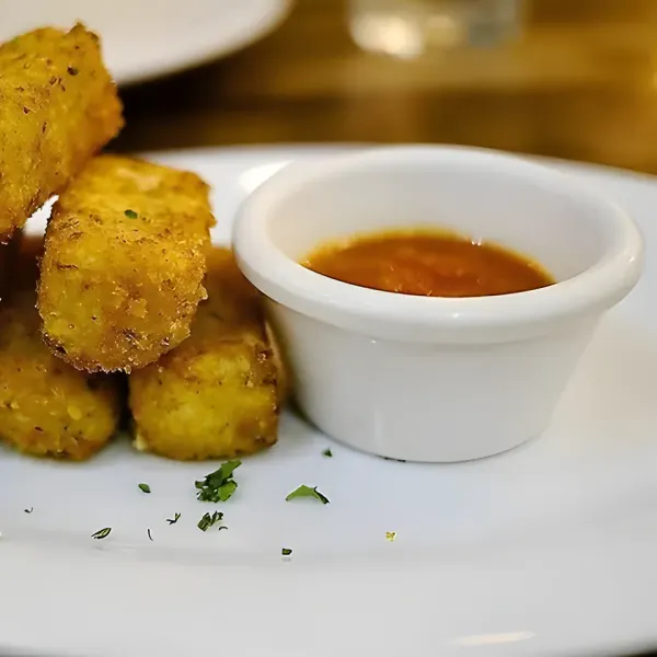 Fried mozzarella sticks with a small dish of marinara sauce.