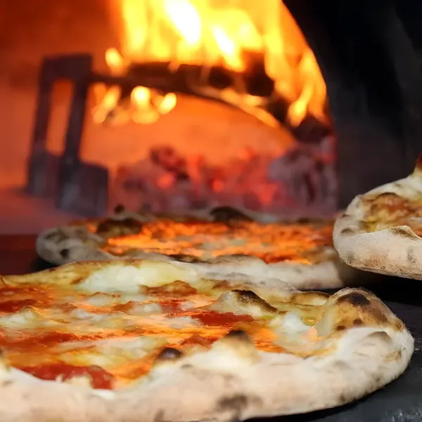 Pizzas baking in an oven with a visible flame